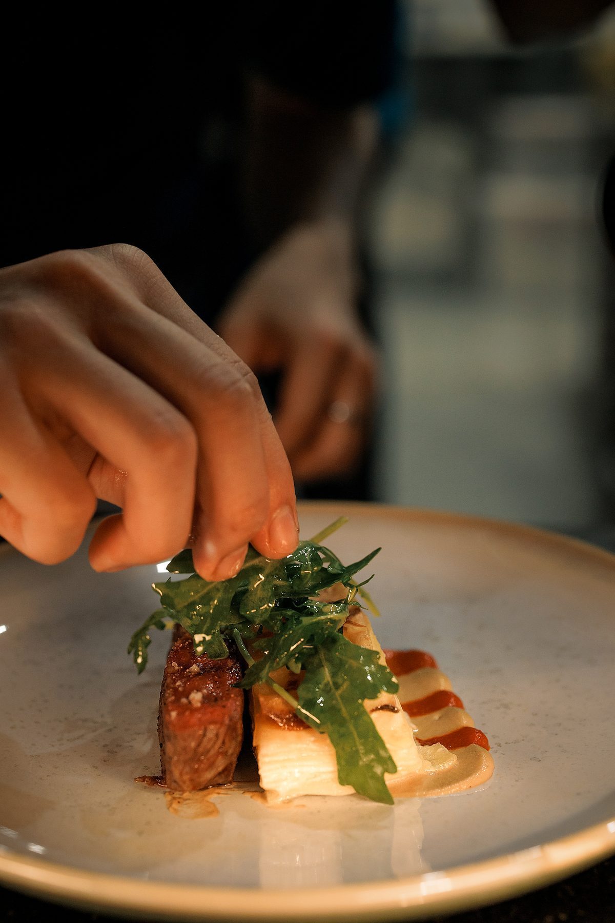 Chef placing fresh herbs on a plated dish