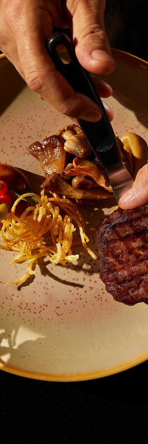 Chef's hands plating beef with autumn vegetables